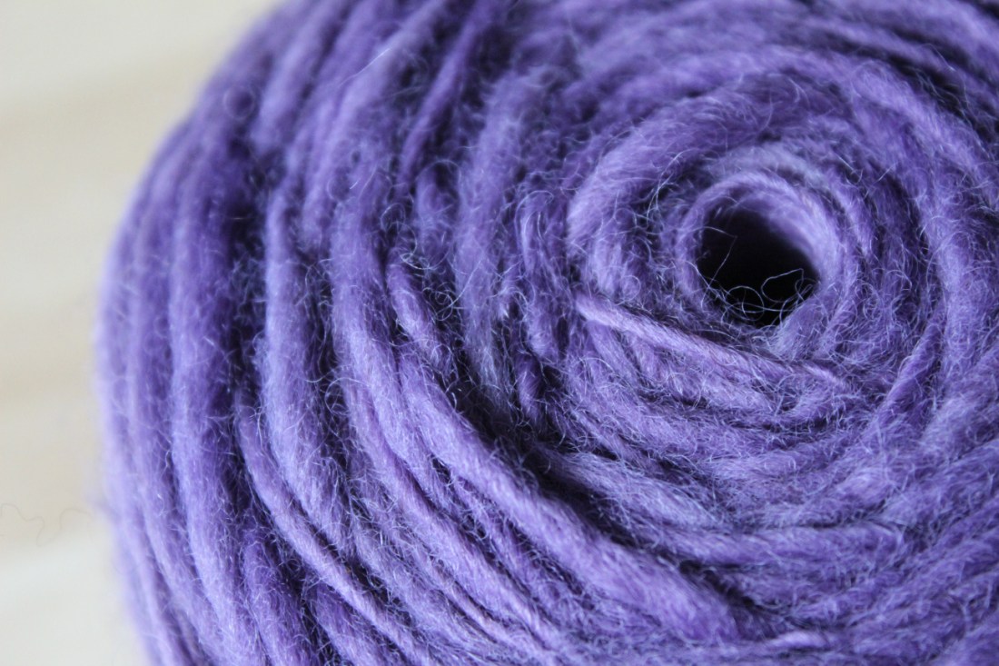 Knäuel lavendellila Garn, kreisrund aufgewickelt.