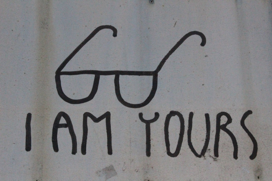 Foto von Street Art: in Versalien "I AM YOURS", darüber eine simple Lesebrille gemalt, wie mit dickem Edding.
