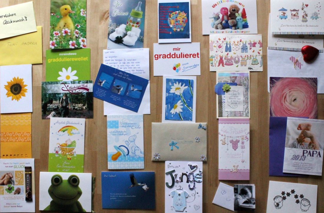 Karten zur Geburt des Kindes, auf dem Tisch, sortiert nach Farben. Links die gelben Karten, dann die grünen, die blauen, die lila-farbenen und die rosanen.