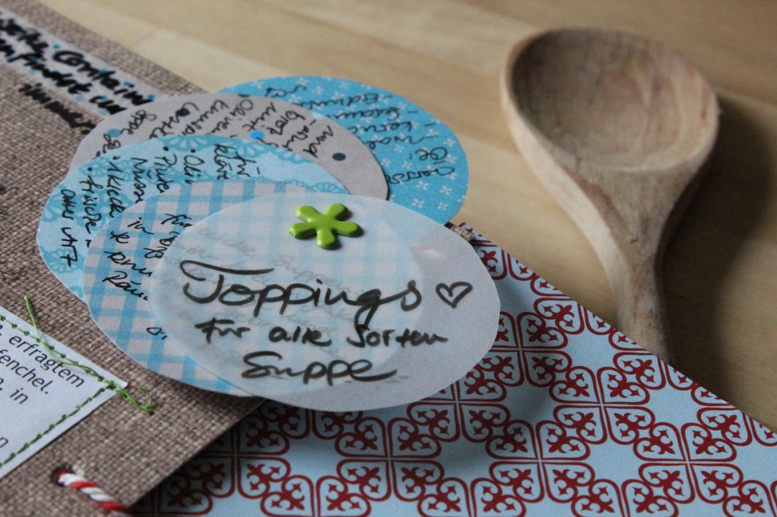 Kreise aus verschiedenem Papier, auf den Toppingmöglichkeiten stehen, so ins Buch gemacht, dass sie sich auffächern lassen.